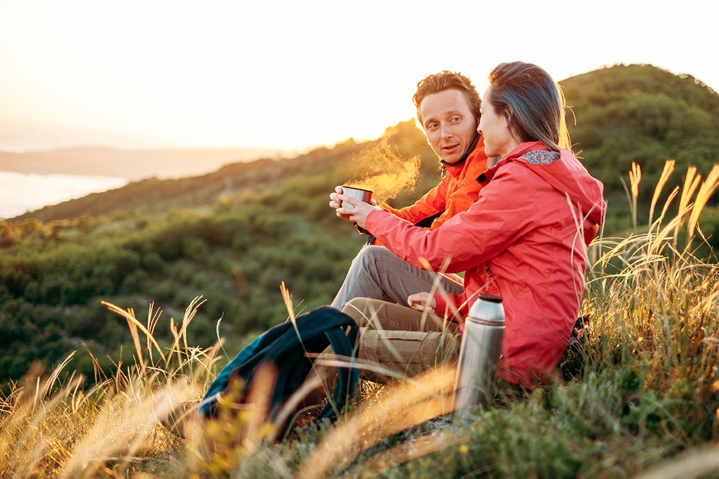 Pärchen macht Pause beim Wandern und genießt heißes Getränk aus der Thermosflasche